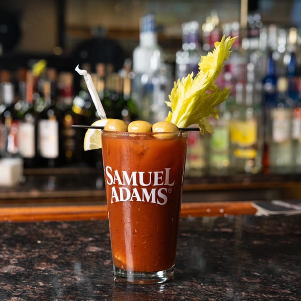Samuel Adams Bloody Mary cocktail with celery, olives, and lemon on a bar.